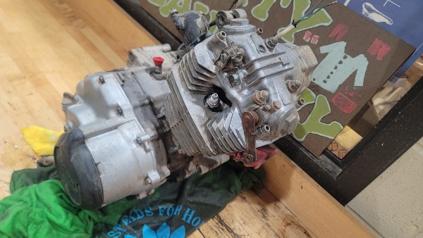 Honda ATC 70 engine sitting on the floor on a green t-shirt, removed from the frame and ready for inspection