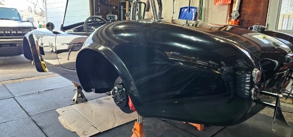 Jim's Cobra kit car — side profile of the black body on jack stands showing the rear fender flare