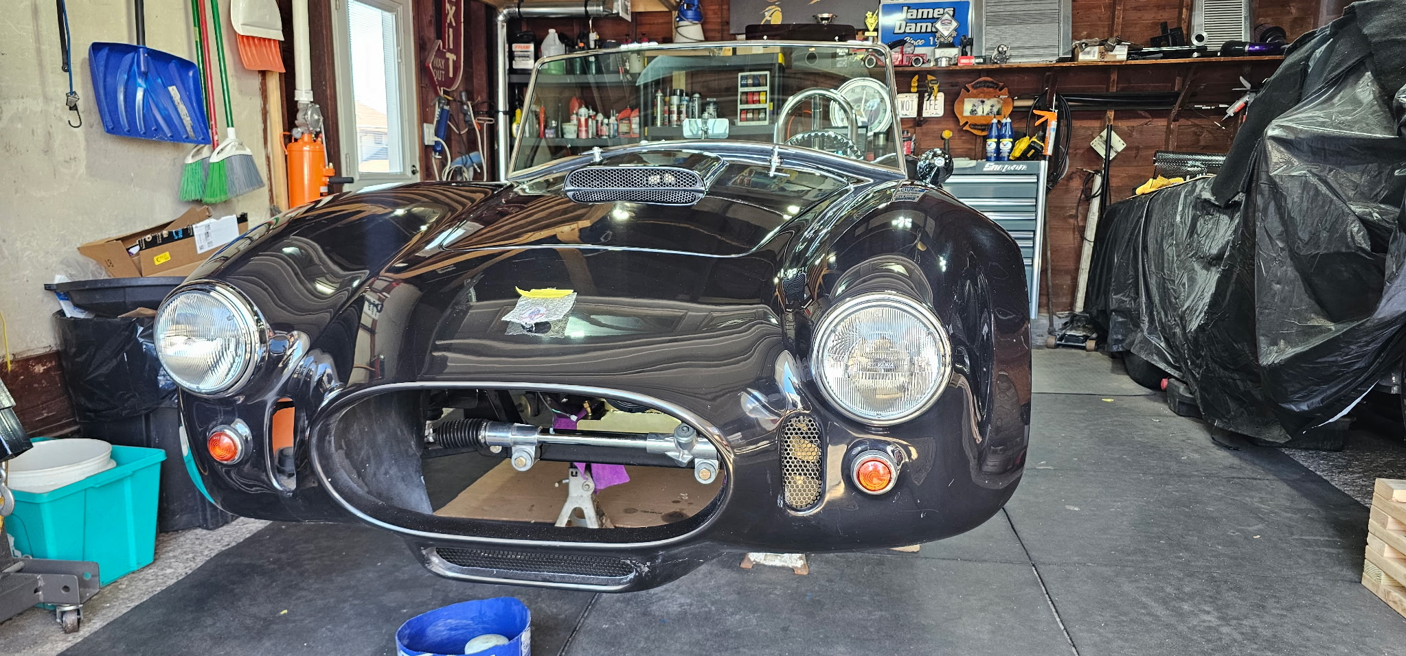 Jim's '67 Cobra kit car — black body, round headlights, sitting in the shop