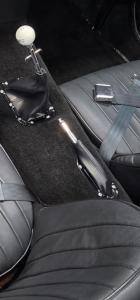 Jim's Cobra interior center console — chrome shifter with white shift knob, leather boot, chrome emergency brake handle, black carpet