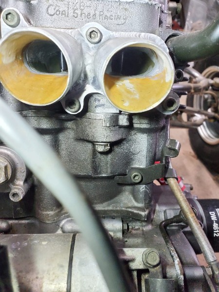 Coal Shed Racing ported head installed on the Raptor 700 engine, both intake ports showing smooth orange epoxy port work, Coal Shed Racing stamp visible on the casting