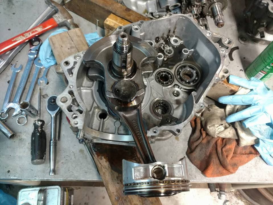 Open Yamaha Raptor 700 engine cases on a workbench, stroker crankshaft and connecting rod installed, ball bearings and transmission gears visible inside
