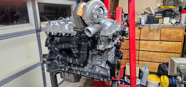 Steve's BMW inline-6 N54 engine on a stand with Precision turbocharger mounted, full engine assembly visible