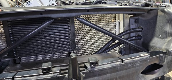 Large front-mount intercooler fitted in the BMW Z4 nose with braided lines visible, engine bay stripped for build
